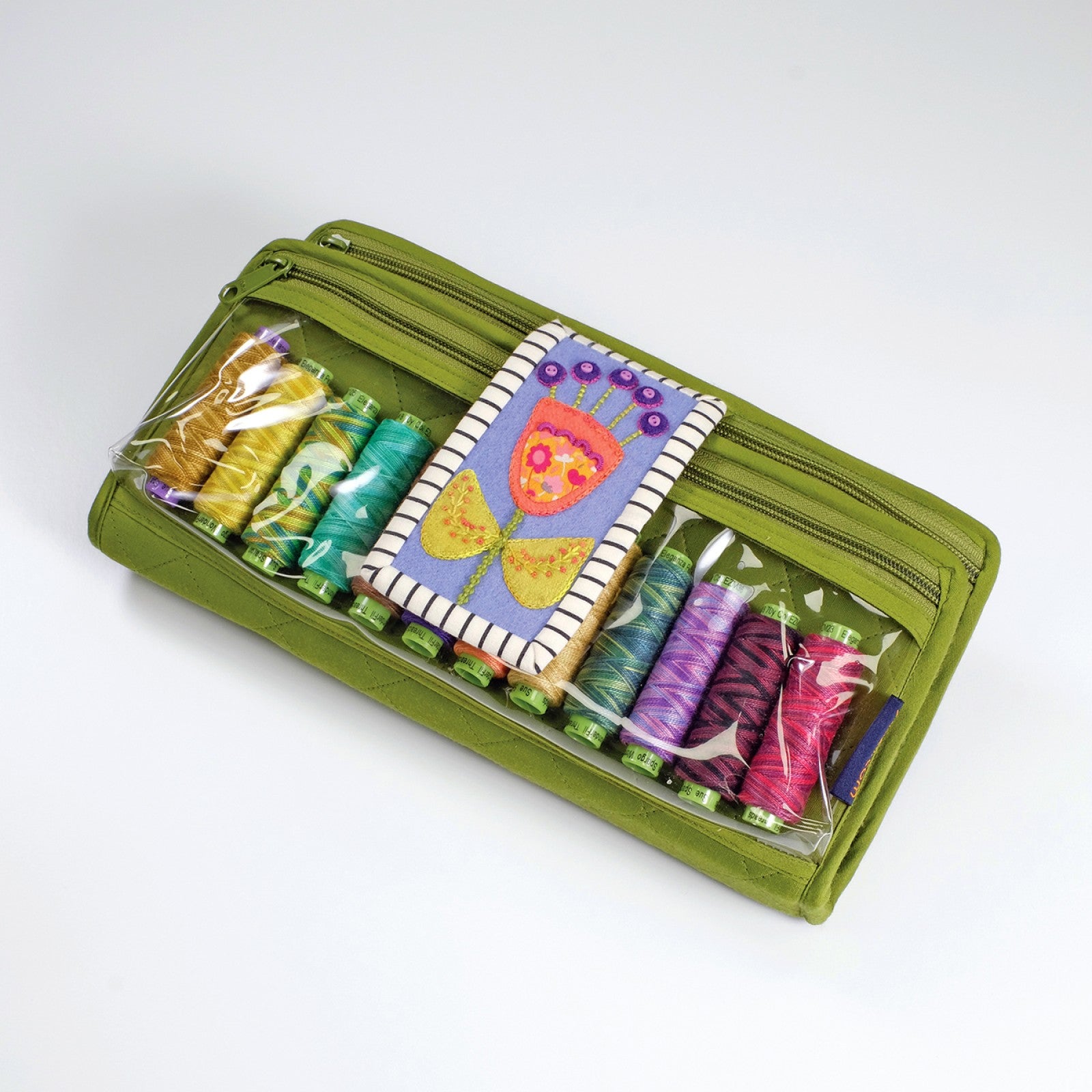 The bonus Rooted Workbox and Needle Book by Sue Spargo of Folk Art Quilts, a green clutch-style organizer holding embroidery thread spools, with an appliqued flower motif on the front flap.
