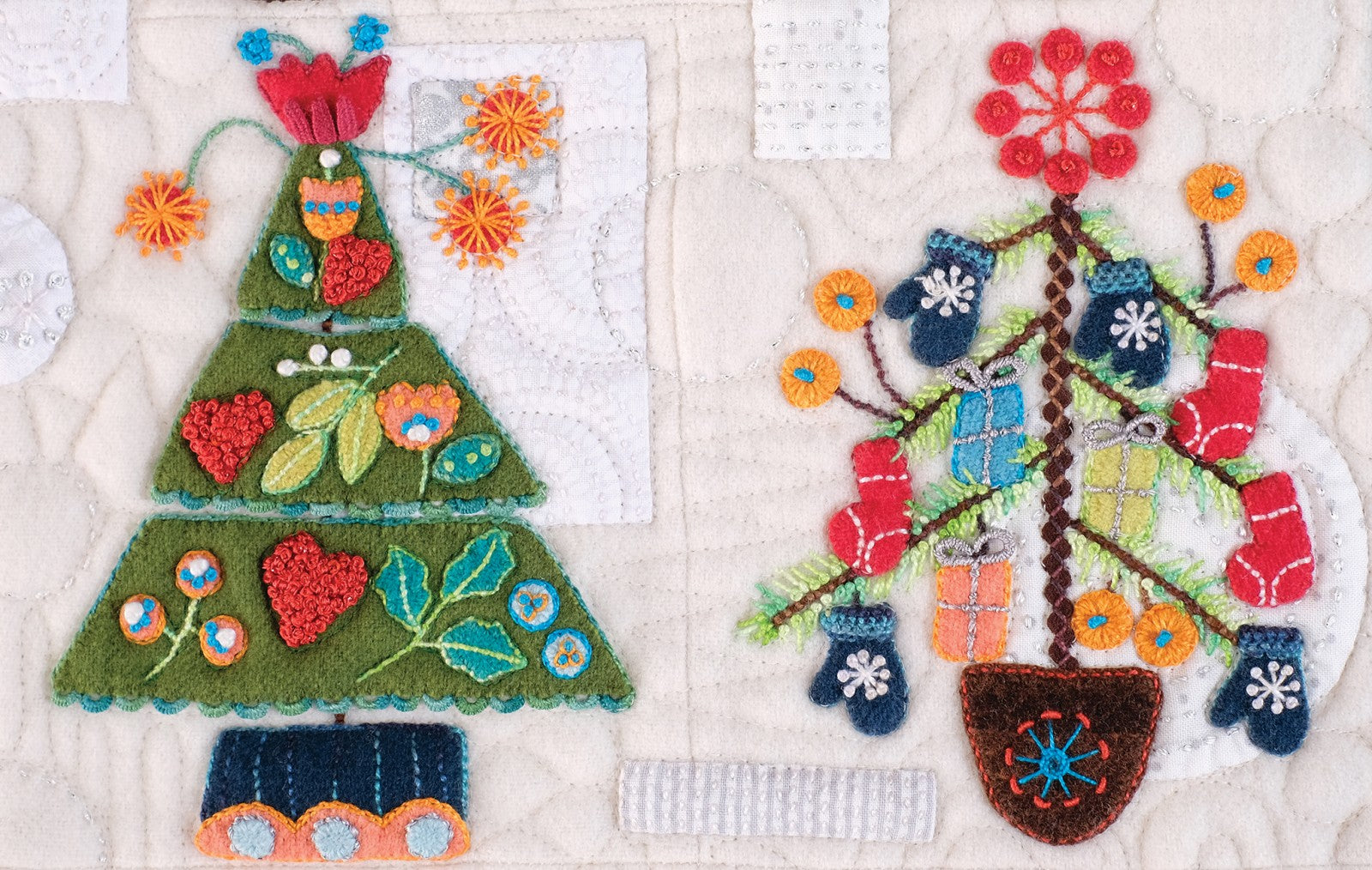 Close detail of Tinsel blocks by Sue Spargo of Folk Art Quilts. One tree is hung with little wool mittens and lights and another with berries and flowers, in layered wool and cotton applique with hand embroidery.