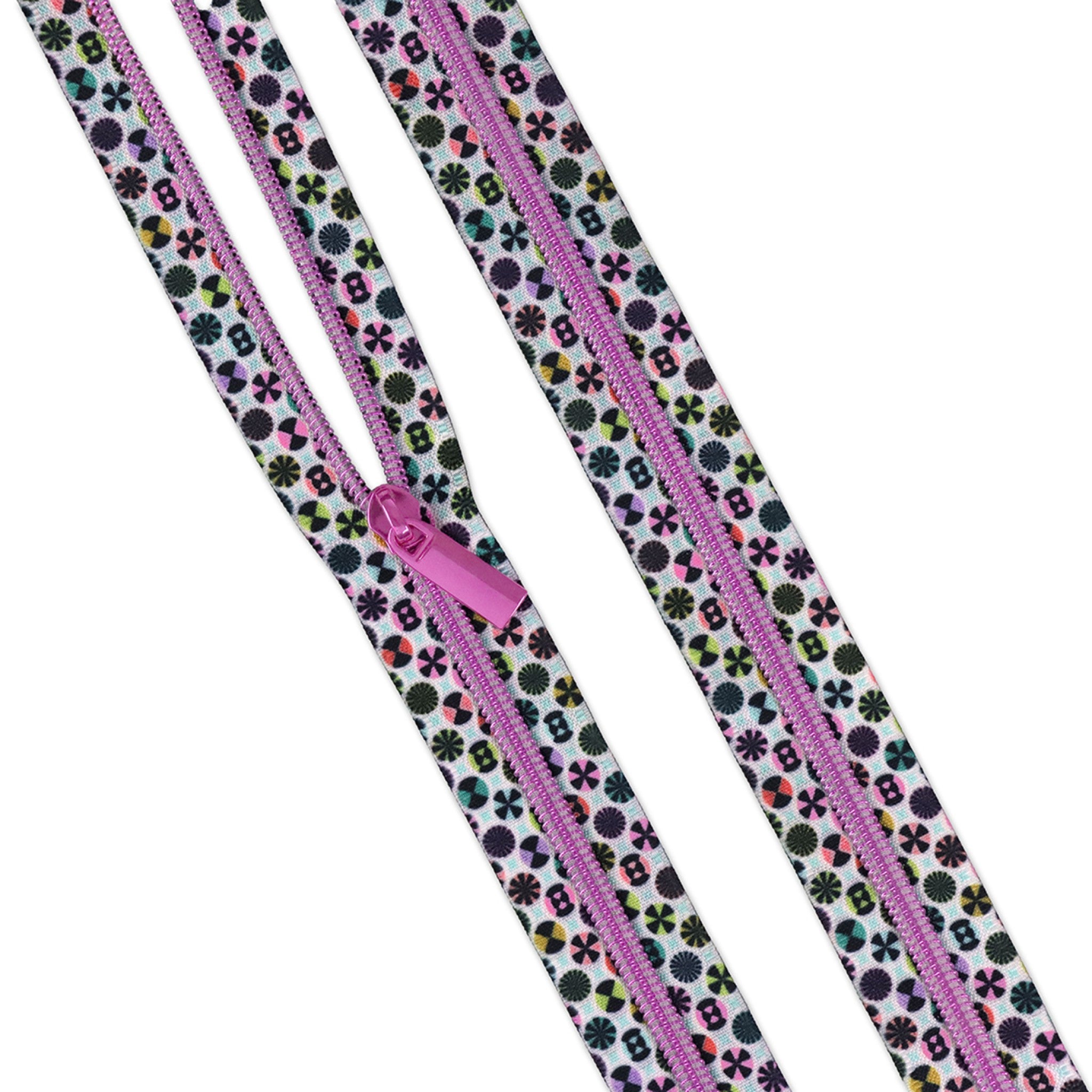 Tula Pink Taffy #5 zipper tape showing white background with dense colorful medallion and floral motif print, with hot pink metallic coils and pull, from the Prince Charming Deja Vu Collection