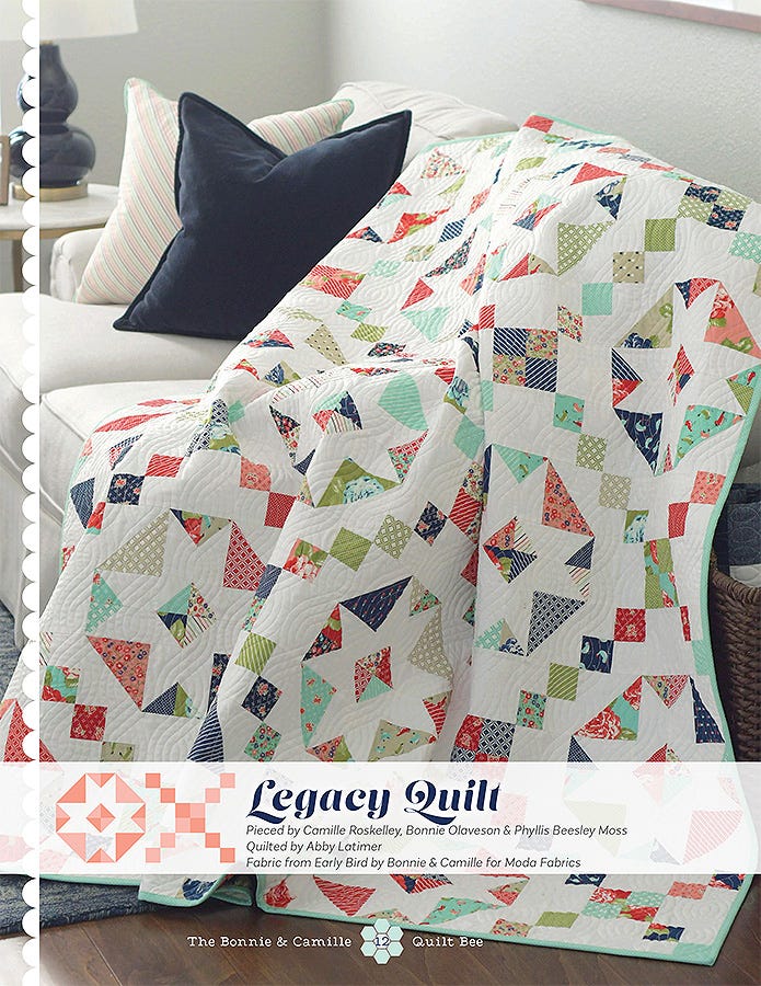 Legacy Quilt from The Bonnie & Camille Quilt Bee, pieced star blocks in navy, red, and aqua draped on a sofa.