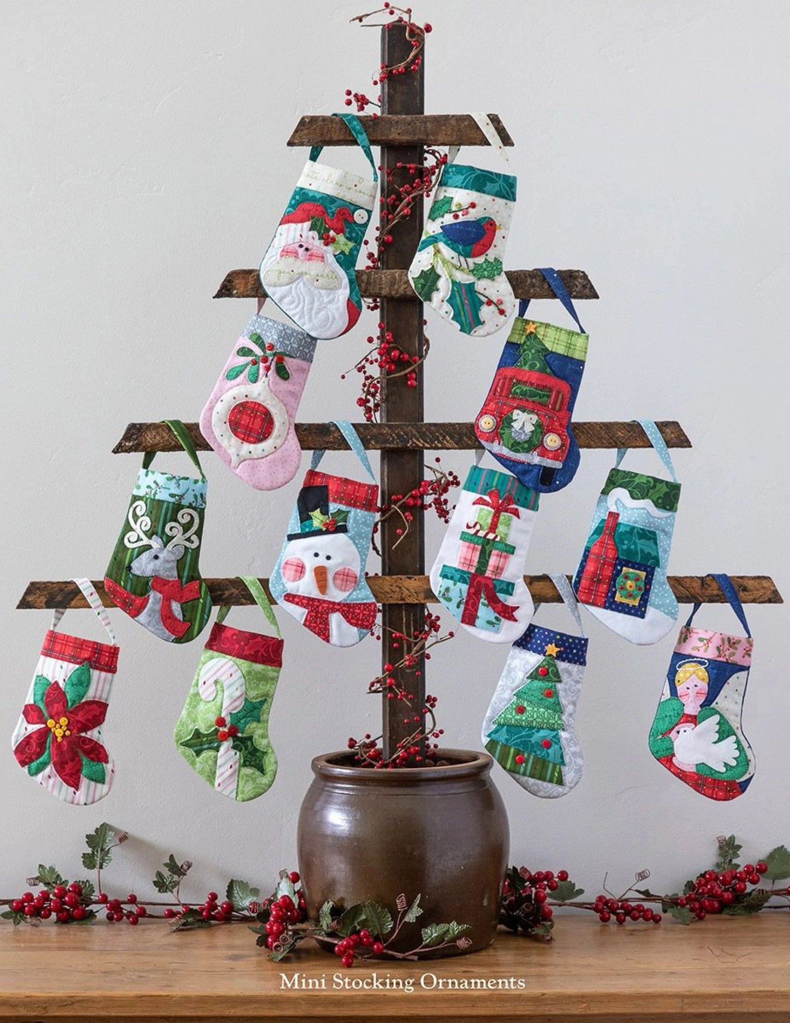 Interior page of the Better Not Pout quilt pattern book by Nancy Halvorsen of Art to Heart, showing a tabletop stand hung with many mini stocking ornaments in assorted Christmas prints.