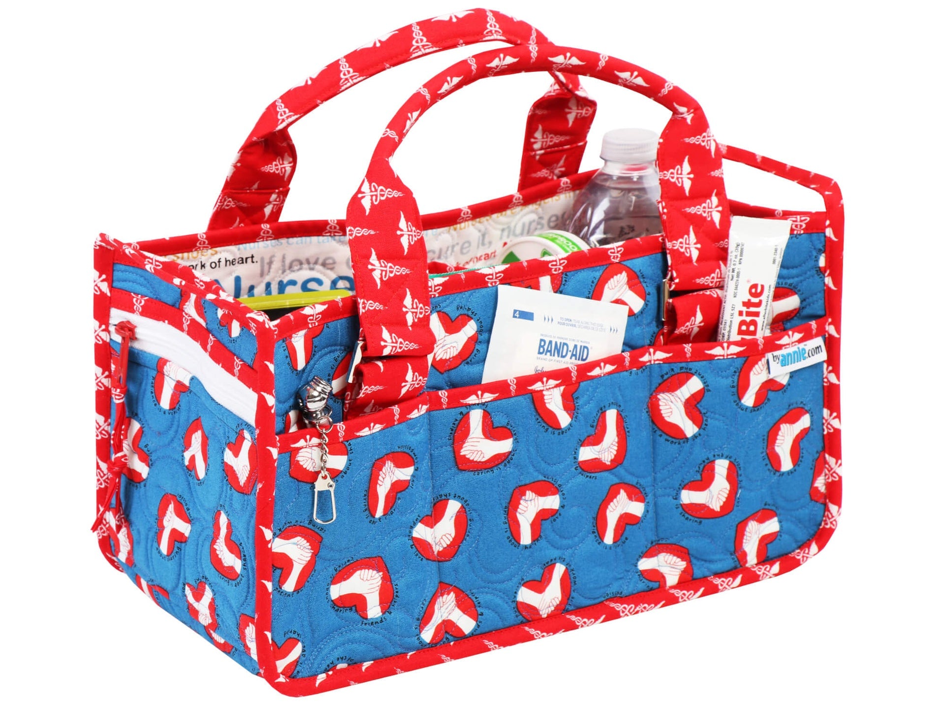 Catch All Caddy 2.0 in a red, white, and blue print filled with a water bottle, bandages, and a badge, with the zippered end pocket and front slip pockets holding supplies.
