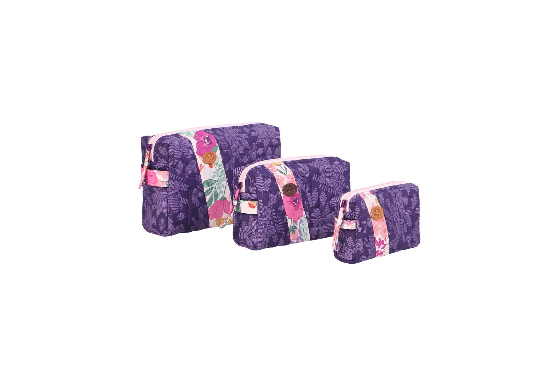 Set of three Ditty Bags sewn in purple batik prints, lined up small, medium, and large, each with side handles and a top zipper.