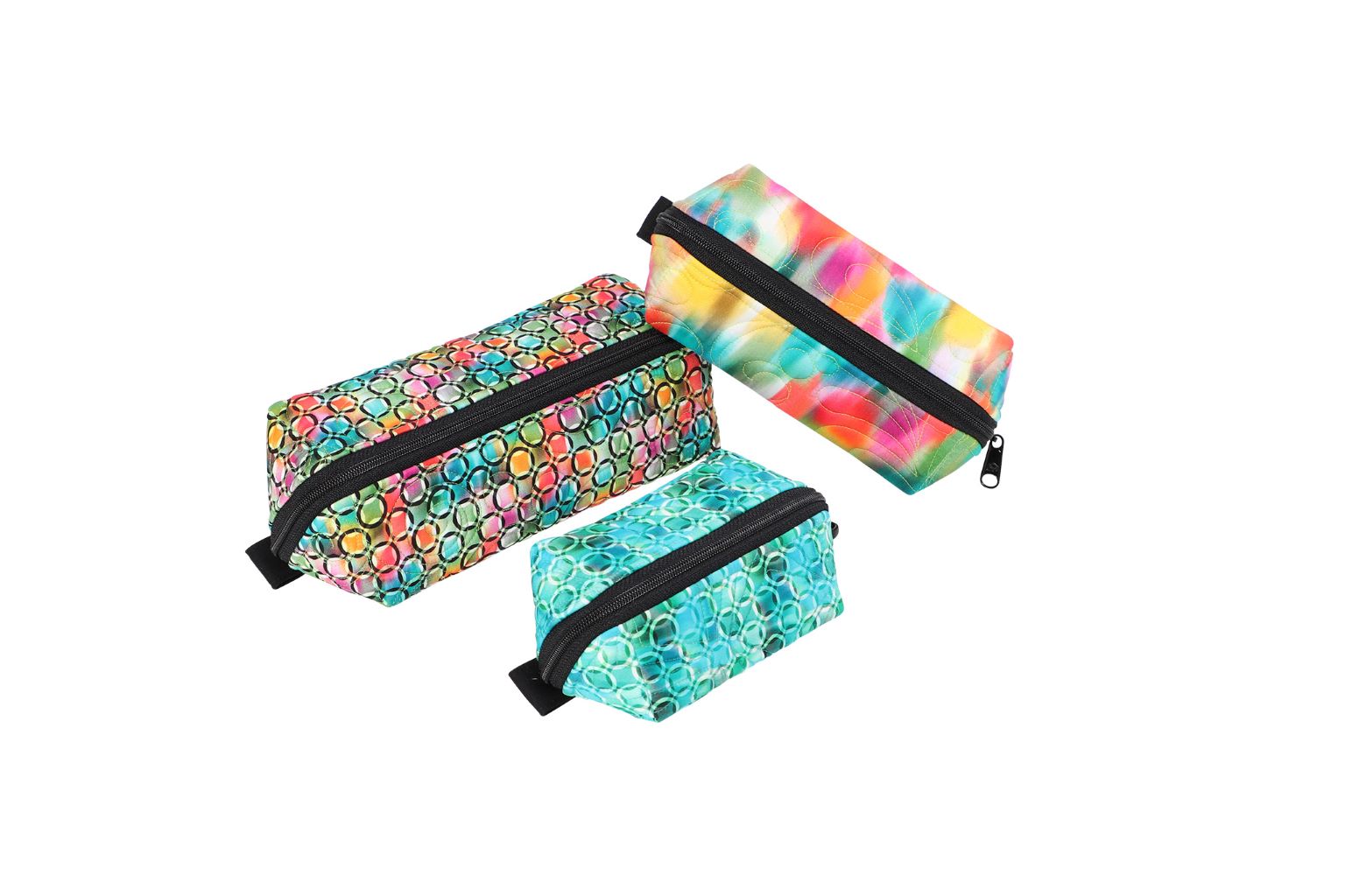 Three Drop Zone pouches in tie-dye and floral prints shown zipped closed.