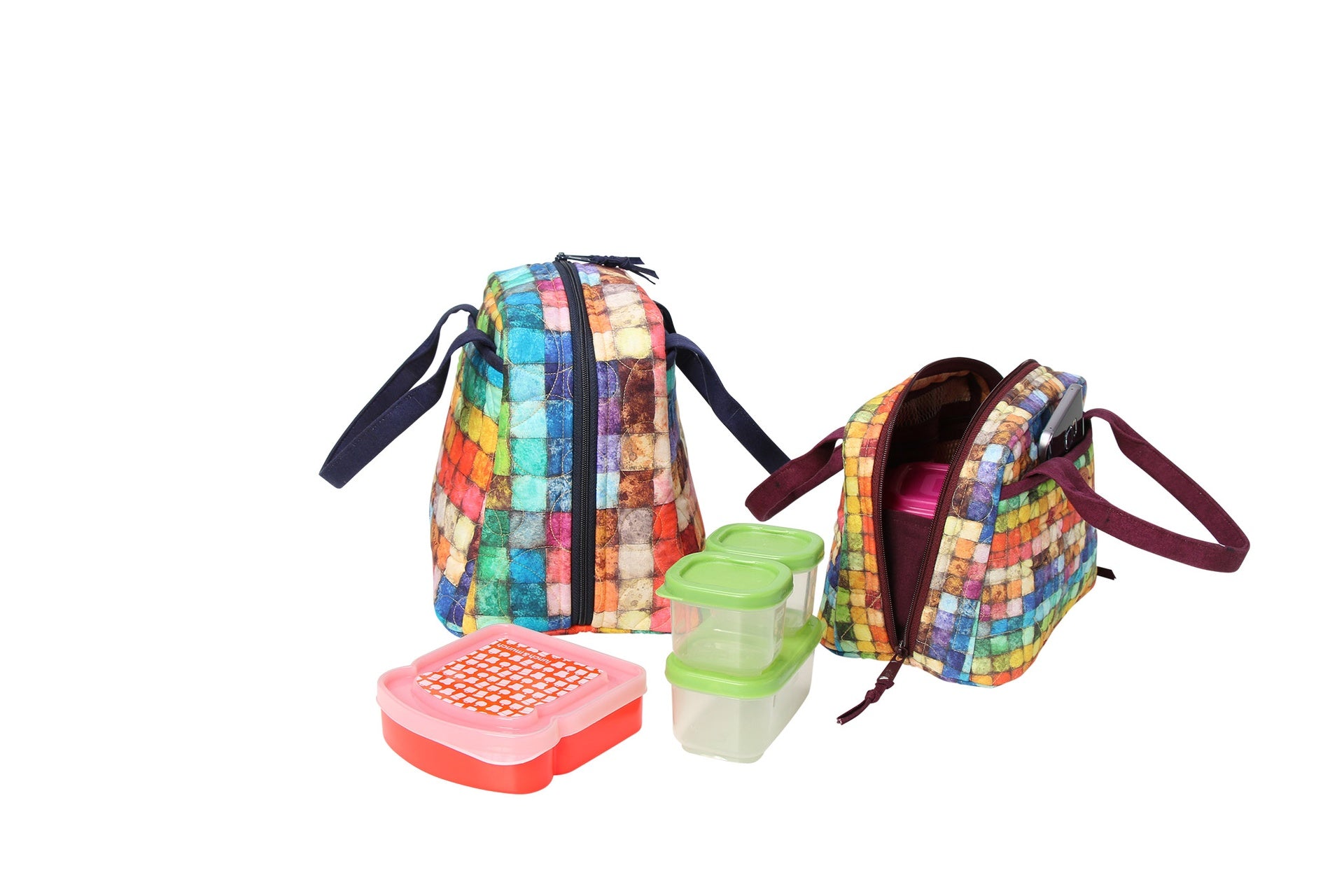 An Out to Lunch bag in a colorful patchwork print shown open from the side next to food containers, showing the side-to-side zipper, interior, and mesh pocket.