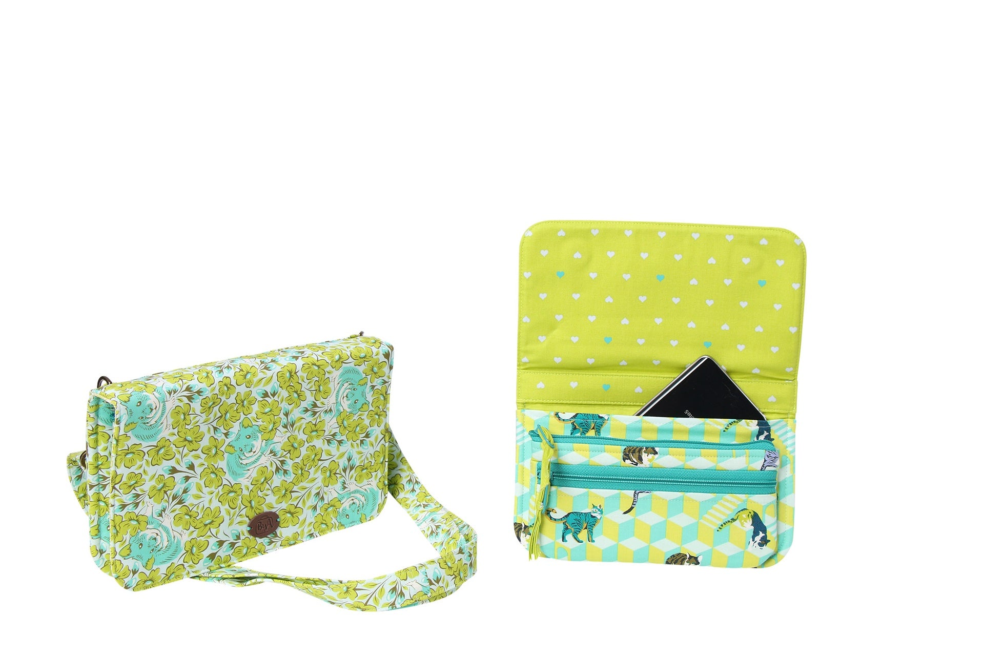 A Payday wallet in a green polka-dot print shown closed with a crossbody strap and open to reveal card slots and a zippered pocket holding cards.