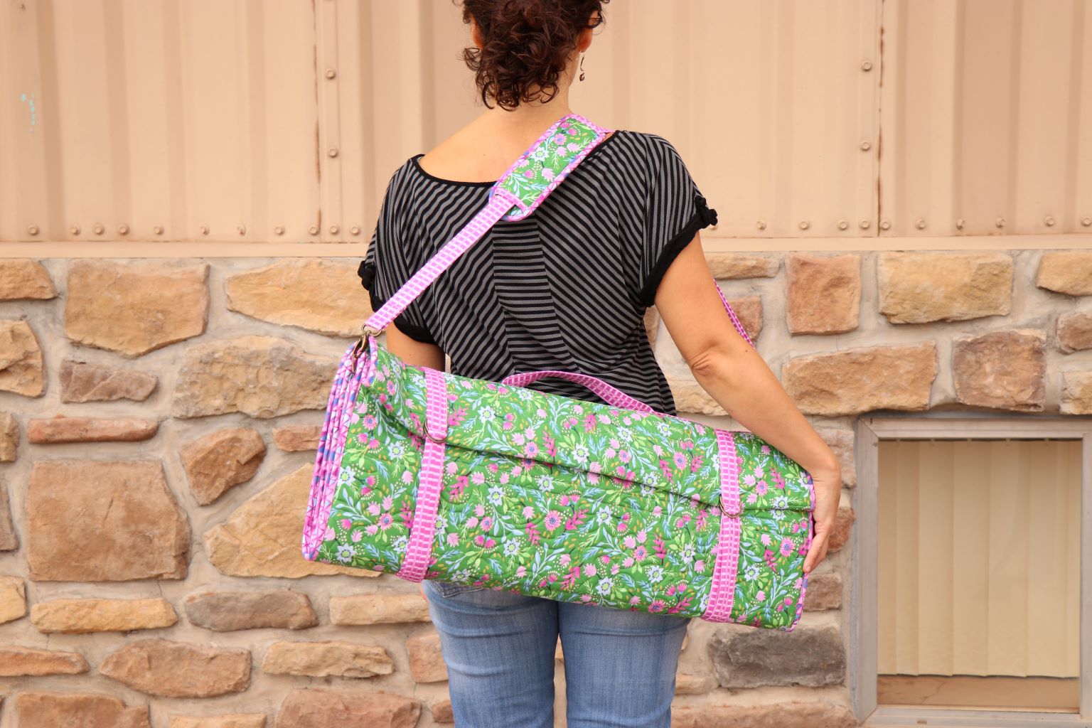 A person carrying a folded Ruler Wrap over the shoulder by its padded strap.