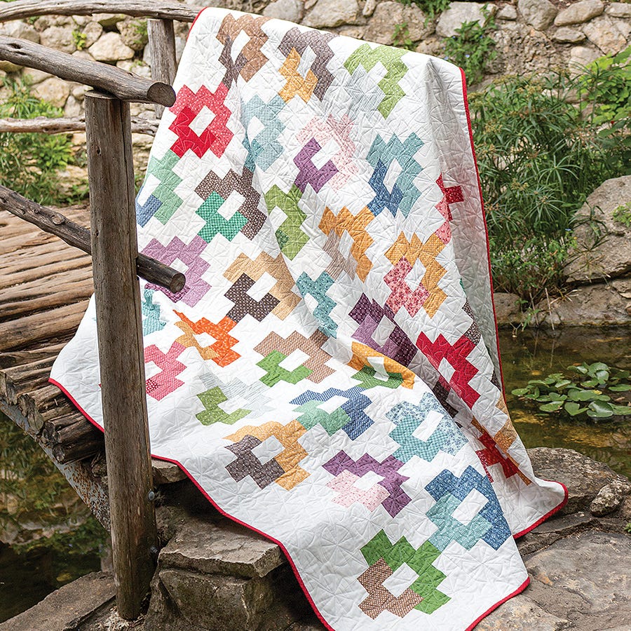 Baguette Quilt from Simply Jelly Rolls, scrappy chain blocks in multicolor prints on a white background.